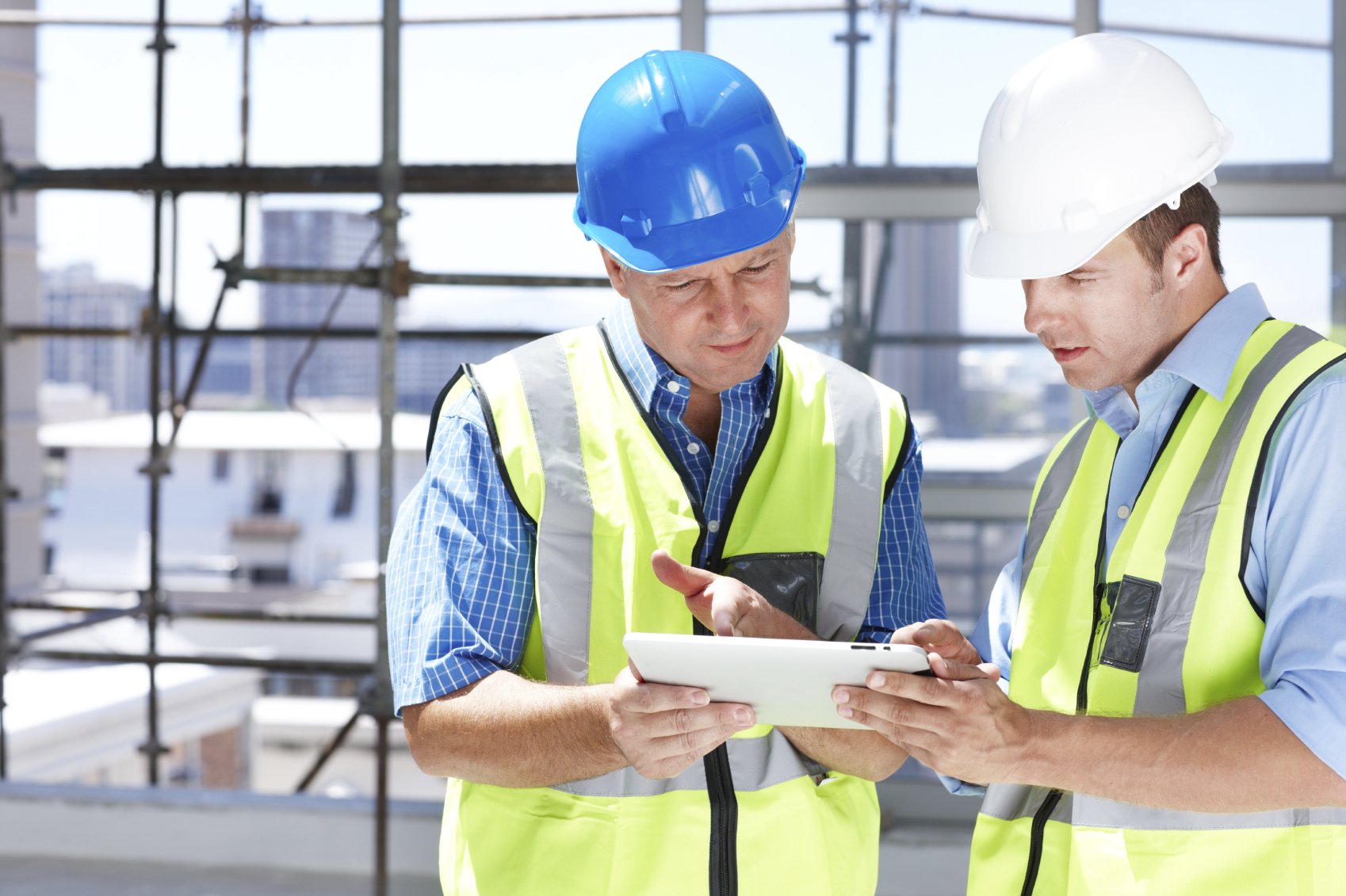 Two engineers working something out on their tablet while at a construction site