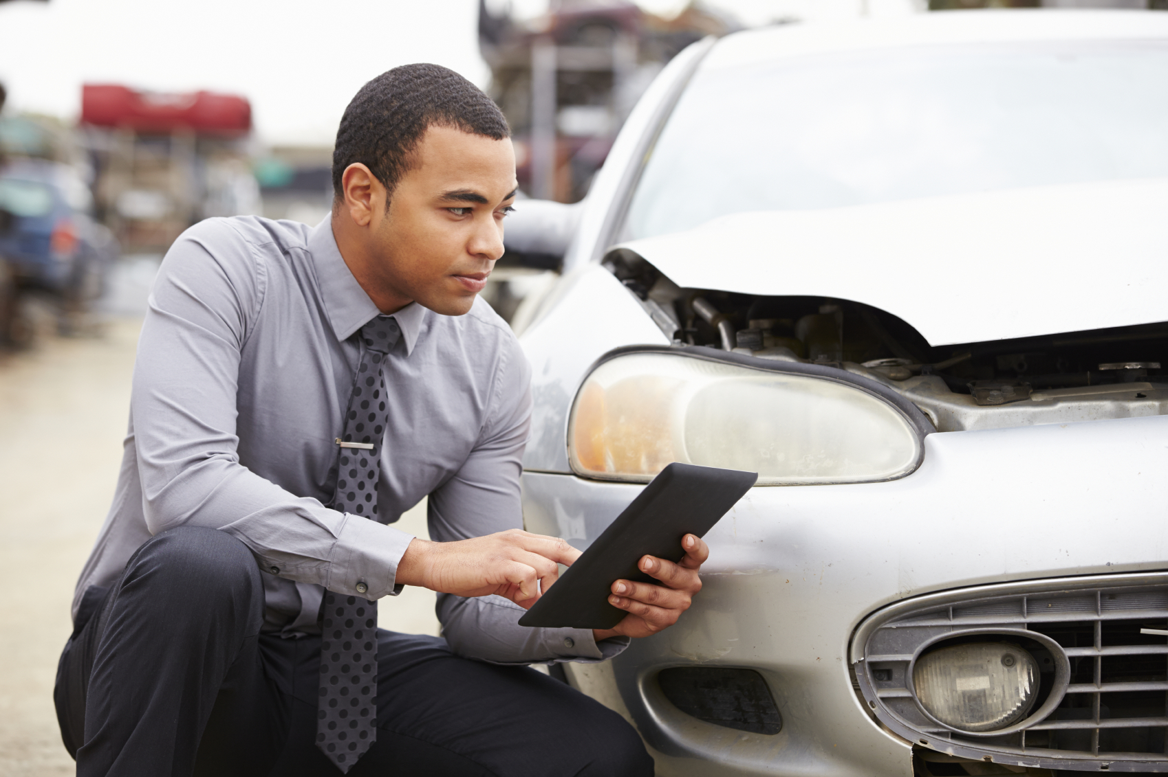 Loss Adjuster Using Digital Tablet In Car Wreck Inspection